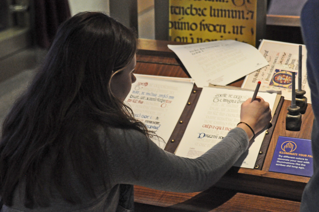 A young visitor tries her hand at hand-copying script